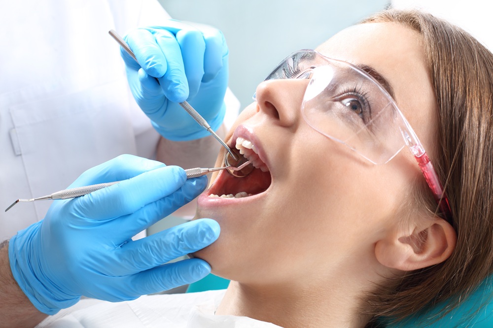 Dental Examination Close-Up – Union Square Oral Surgery A close-up of a woman wearing protective glasses receiving a dental check-up with metal instruments – Union Square Oral Surgery